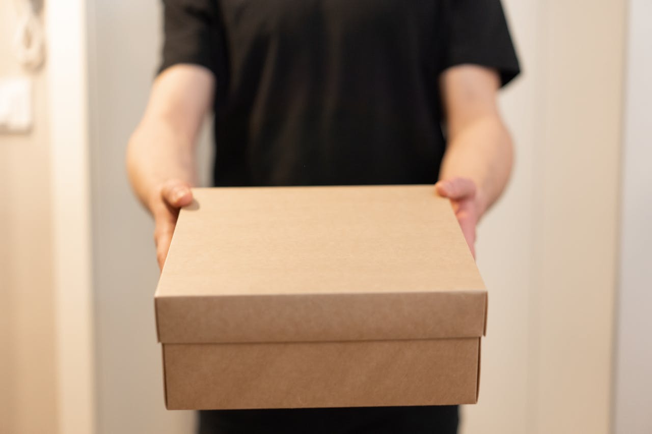 Home Close-up of a person holding a cardboard box, ideal for delivery service concepts.
